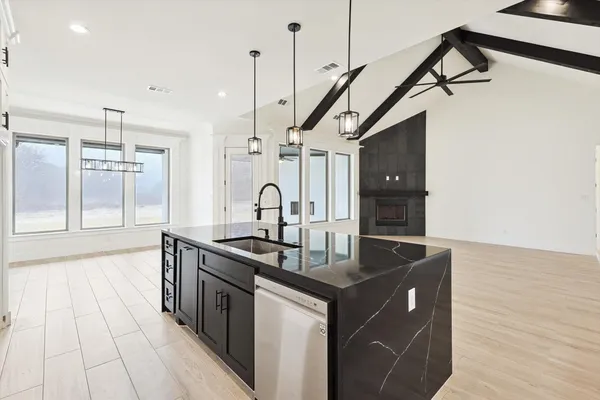 a kitchen with stainless steel appliances granite countertop a sink a stove and a wooden floor