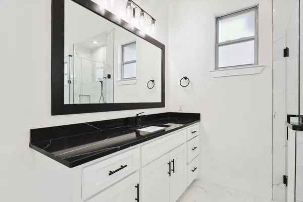 a bathroom with a granite countertop sink and a mirror