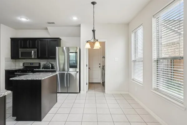 a kitchen with stainless steel appliances granite countertop a refrigerator a sink a stove top oven and a window