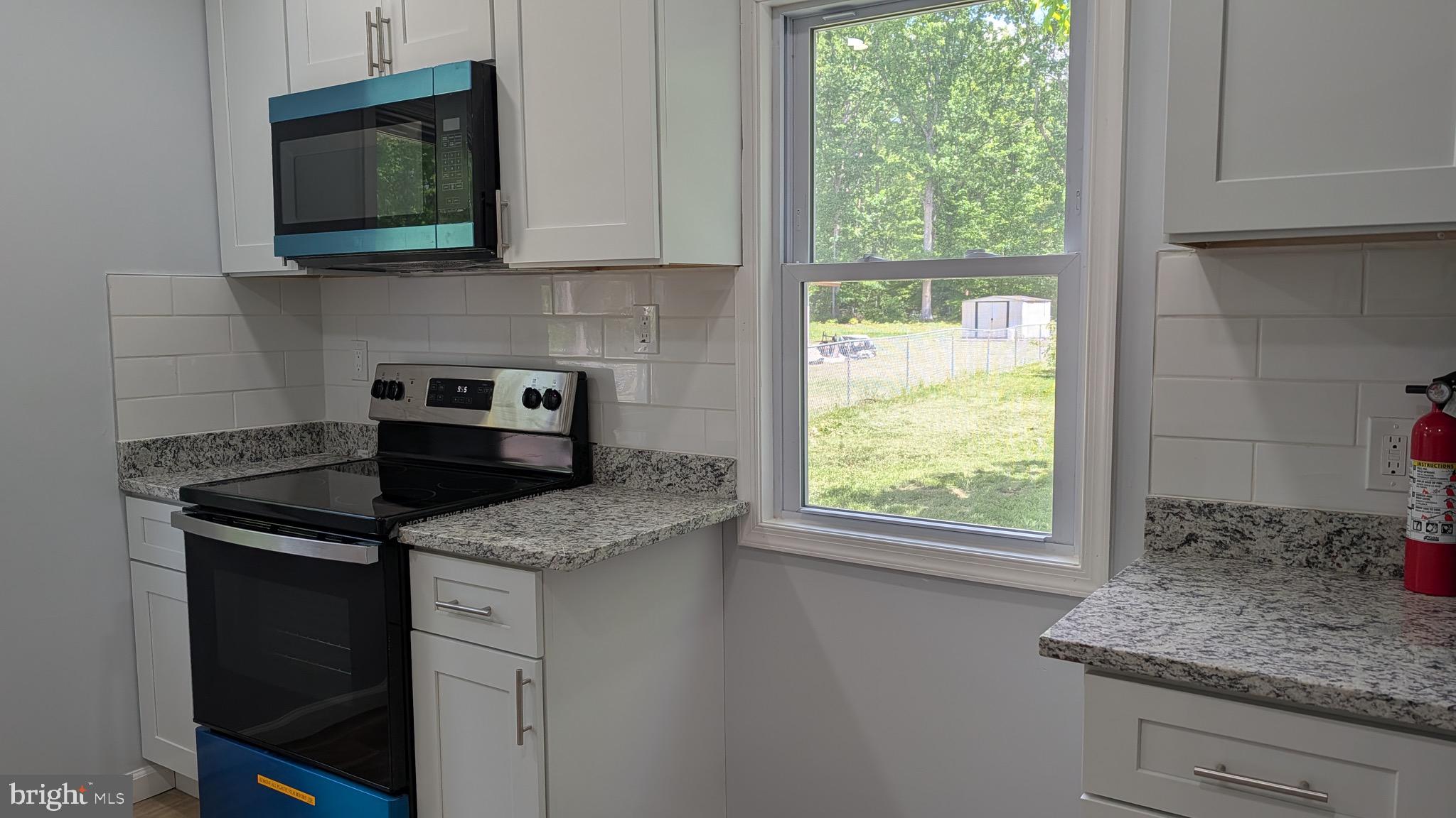 16110 Bealle Hill Road Waldorf, MD 20601 - Photo 12 of 18 a kitchen with granite countertop kitchen island white cabinets and a window