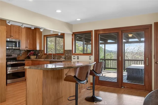 a kitchen with stainless steel appliances granite countertop a stove a refrigerator a sink a dining table and chairs with wooden floor