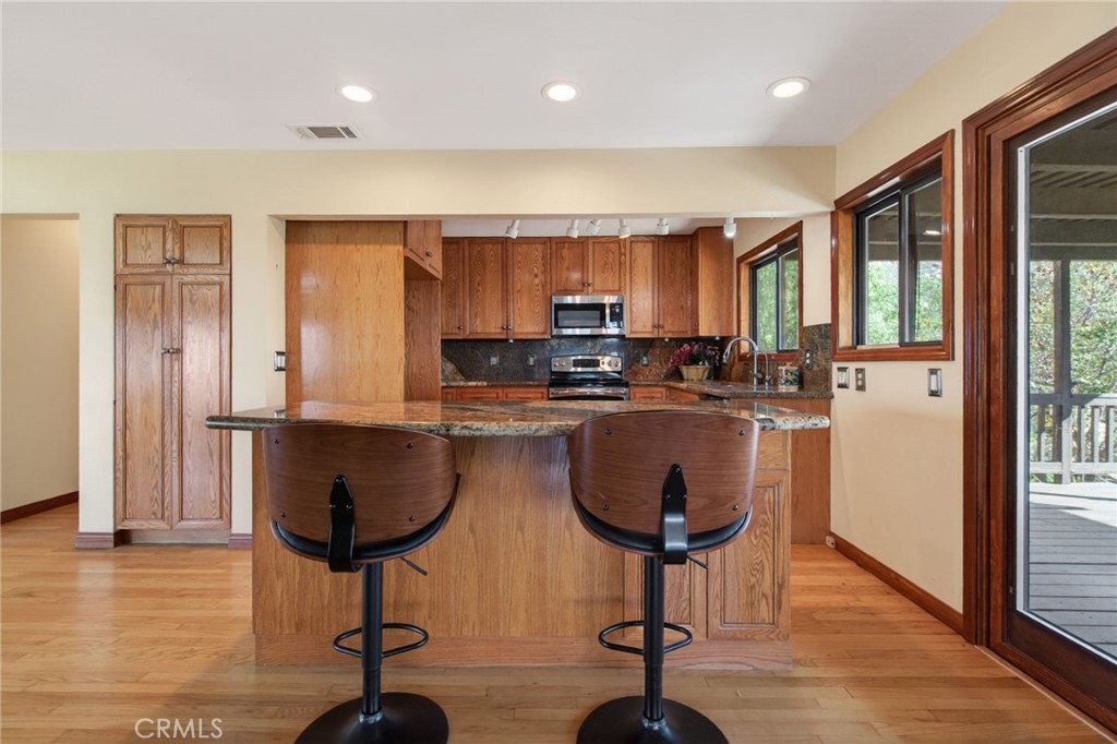 20682 Hill Top Drive Riverside, CA 92507 - Photo 15 of 70 a kitchen with stainless steel appliances granite countertop a stove a refrigerator a sink a dining table and chairs with wooden floor