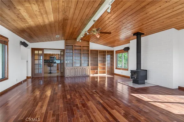 a view of an empty room with window and wooden floor