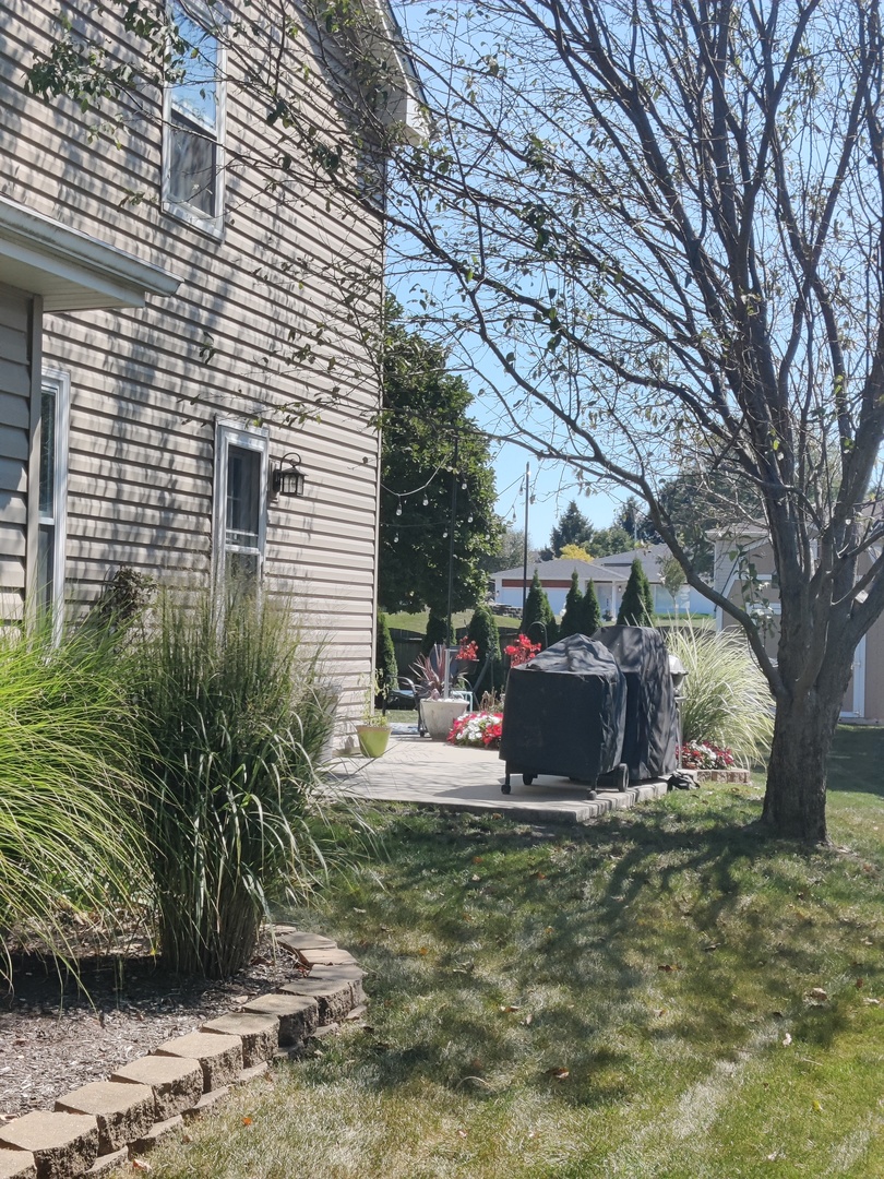 1681 Boulder Ridge Drive Bolingbrook, IL 60490 - Photo 2 of 17 a view of a backyard with table and chairs and a large tree