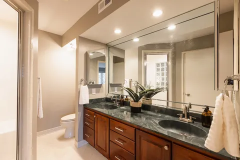a bathroom with a double vanity sink toilet and a mirror