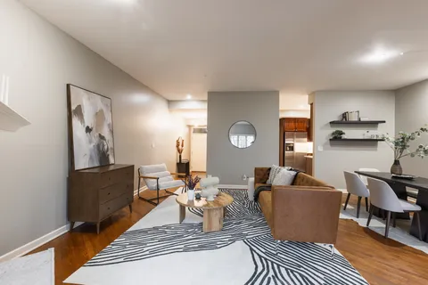 a living room with furniture wooden floor and kitchen view