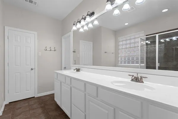 a bathroom with double vanity sinks a vanity a lamp and a mirror