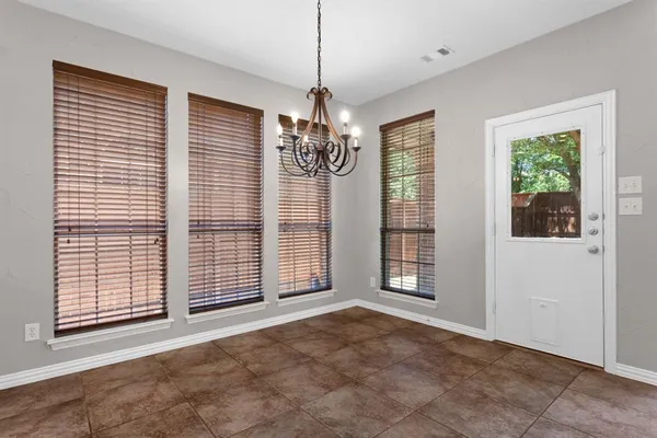 a view of an empty room with window and chandelier fan