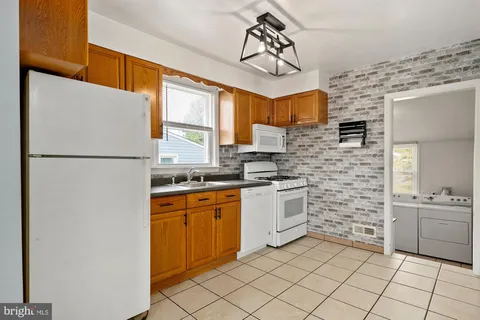 a kitchen with stainless steel appliances granite countertop a sink a stove a refrigerator and white cabinets