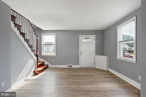 a view of an empty room with wooden floor and windows