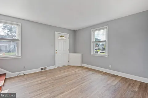 a view of empty room with window and wooden floor