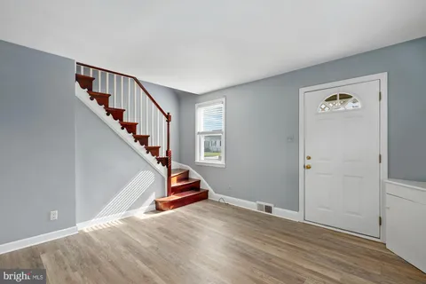 a view of empty room with stairs and wooden floor