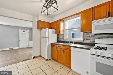 a kitchen with stainless steel appliances granite countertop a refrigerator a sink dishwasher a stove with white cabinets and wooden floor