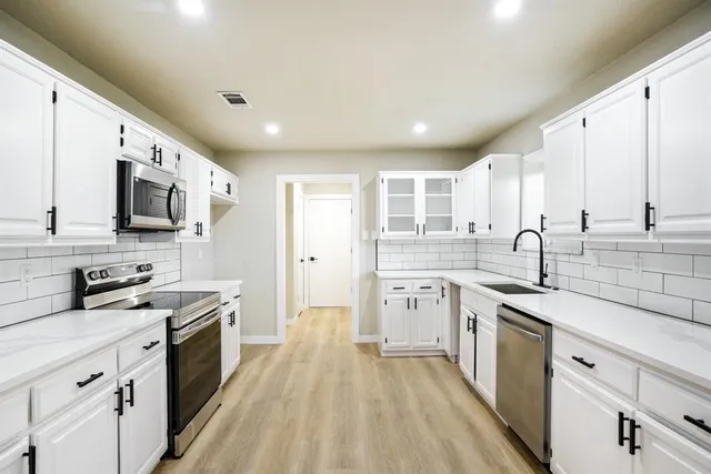 a kitchen with granite countertop a sink stainless steel appliances and white cabinets
