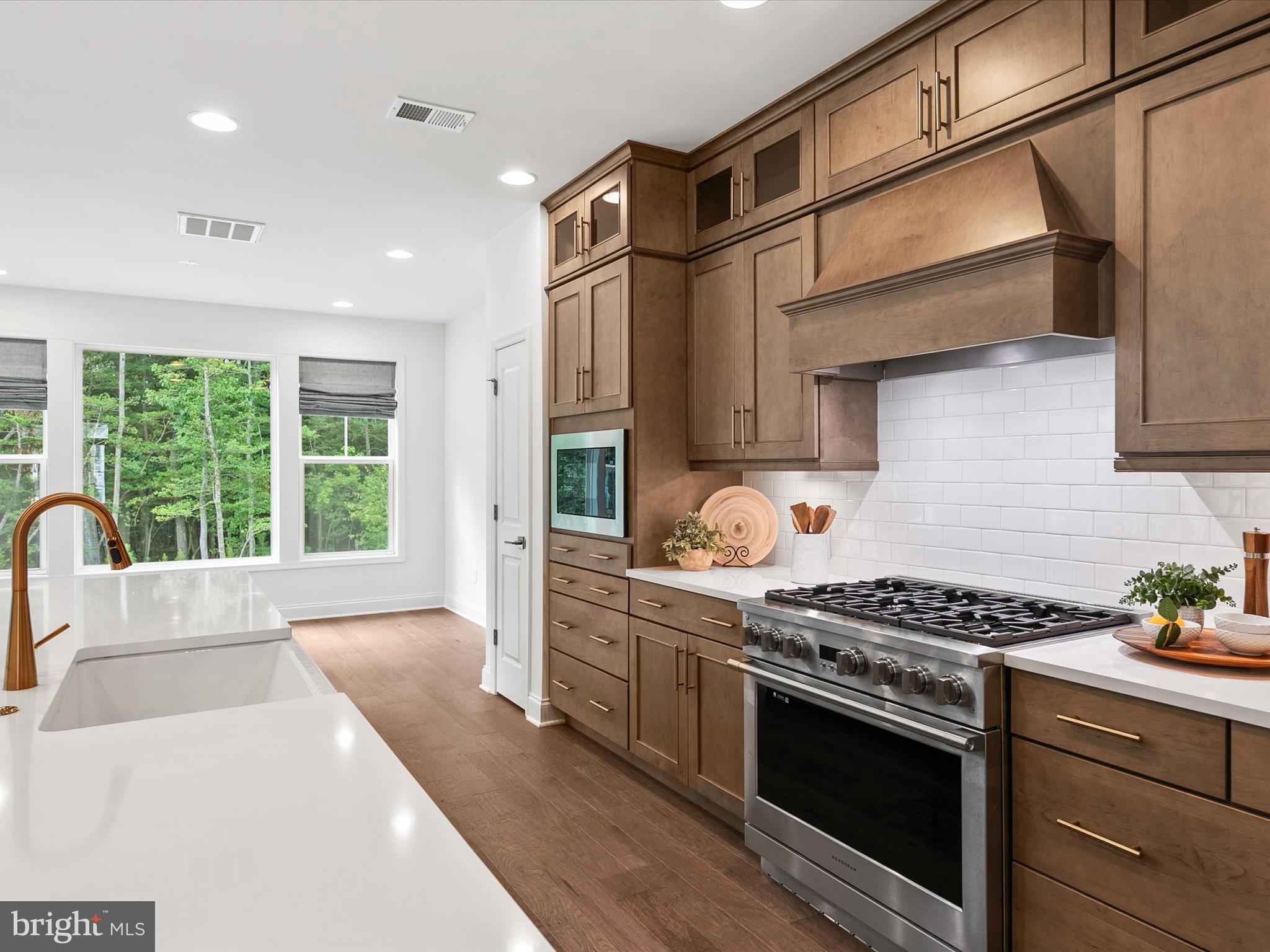21650 Eastbridge Loop Lewes, DE 19958 - Photo 23 of 106 a kitchen with stainless steel appliances granite countertop a stove a sink dishwasher and white cabinets with wooden floor