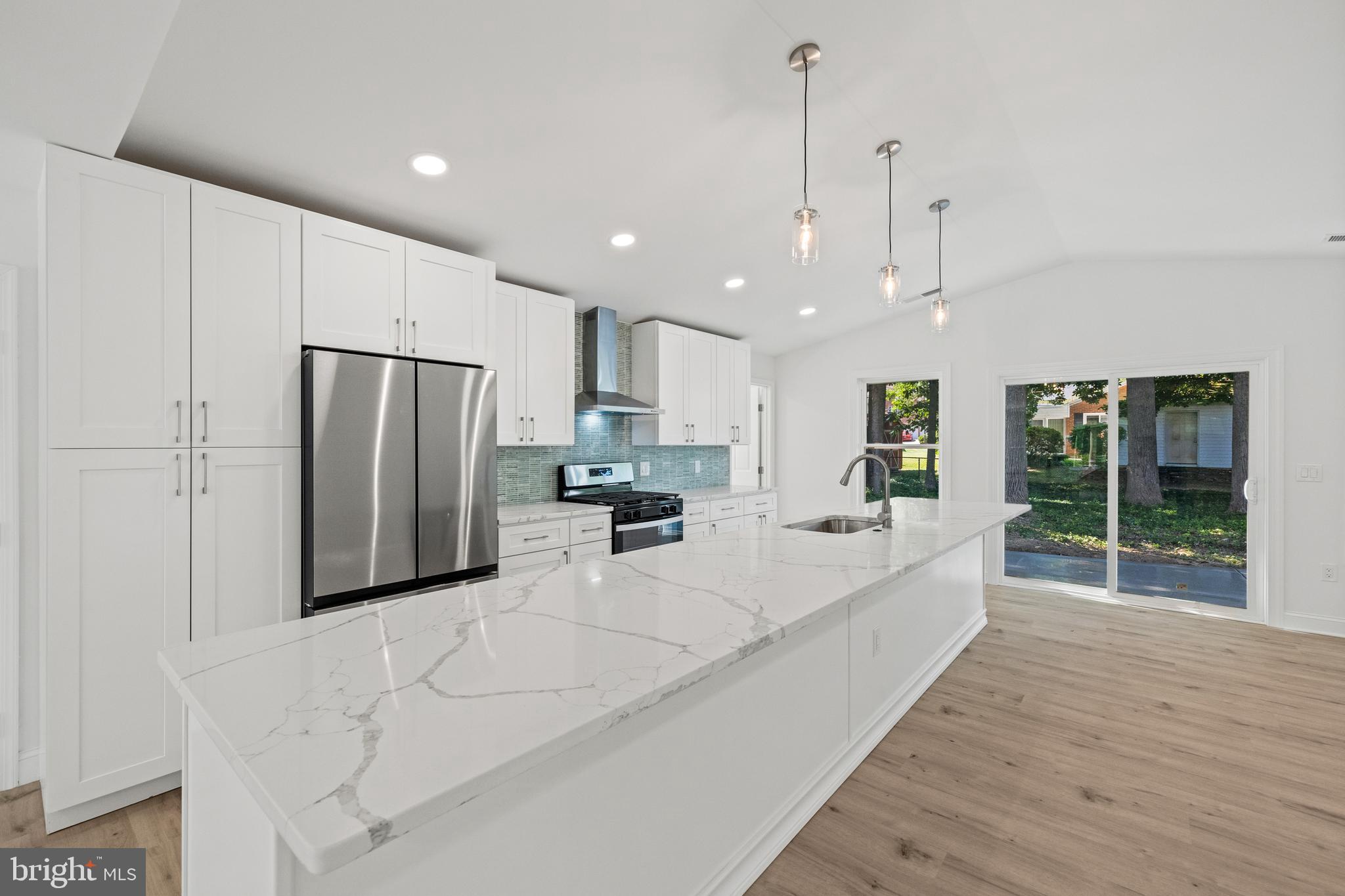 7129 Catlett Street Springfield, VA 22151 - Photo 13 of 34 a large white kitchen with kitchen island a large window and stainless steel appliances