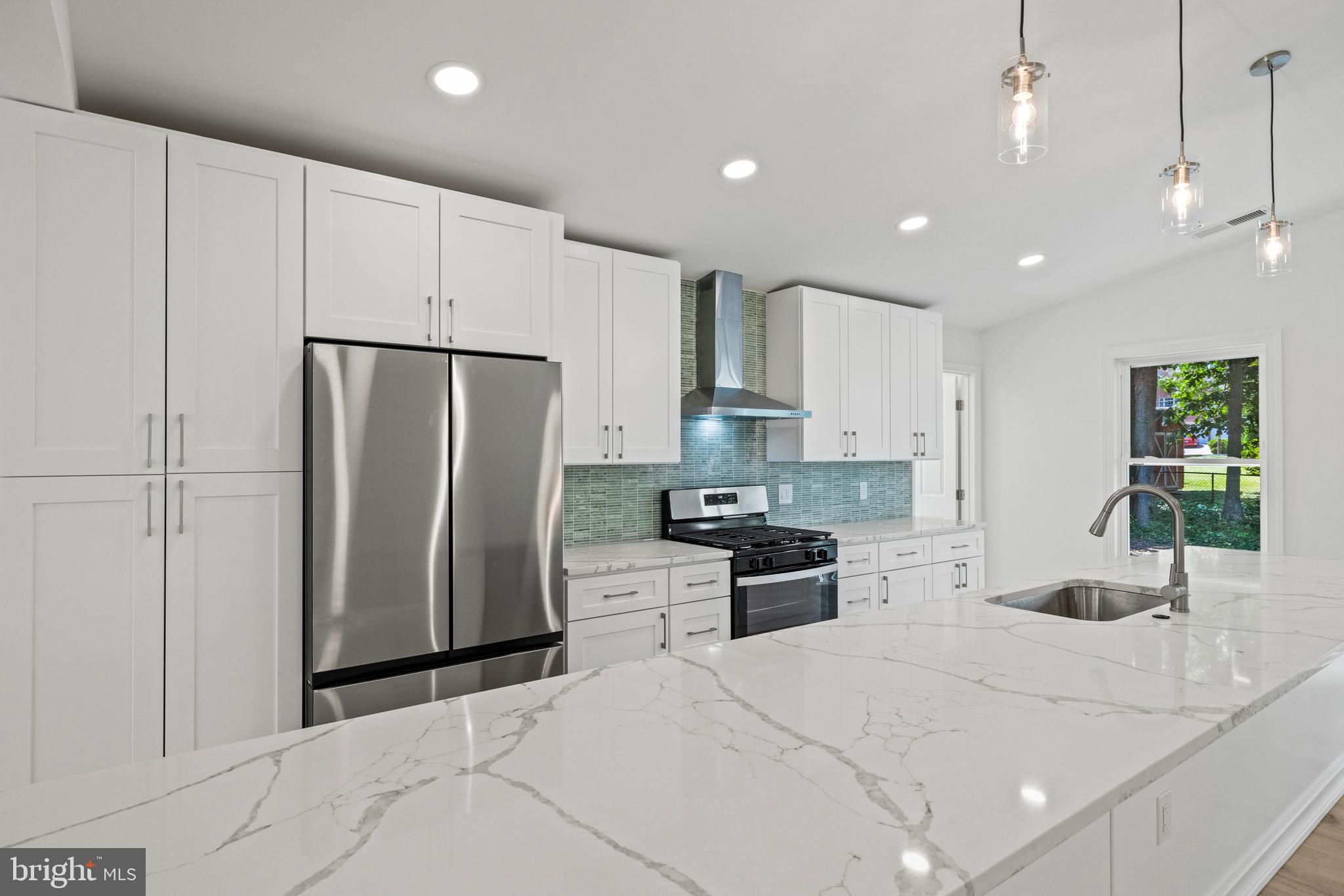 7129 Catlett Street Springfield, VA 22151 - Photo 15 of 34 a kitchen with stainless steel appliances kitchen island granite countertop a refrigerator a sink a stove a microwave oven with white cabinets