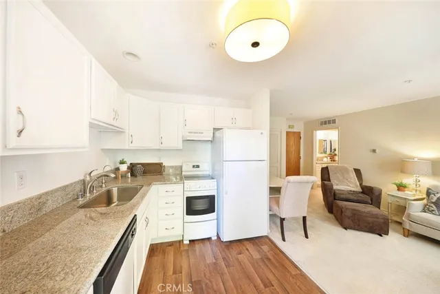 a kitchen with granite countertop a stove a sink a dining table and chairs with wooden floor