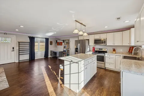 a large kitchen with stainless steel appliances granite countertop a lot of counter space and wooden floors