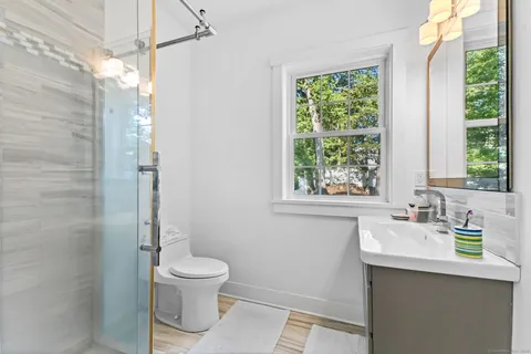 a bathroom with a toilet a sink a mirror and a window