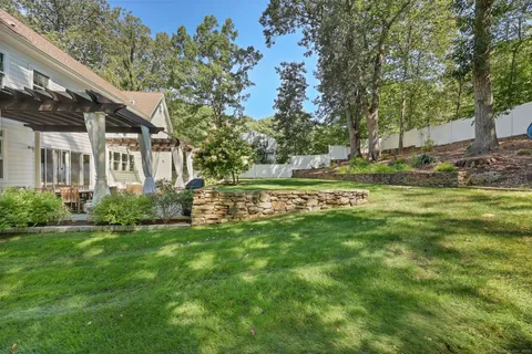 a view of a house with a big yard and large trees