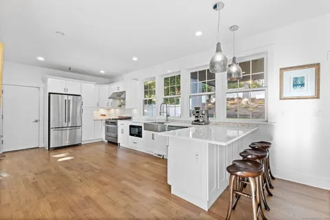 a kitchen with stainless steel appliances a sink a stove a refrigerator cabinets and wooden floor