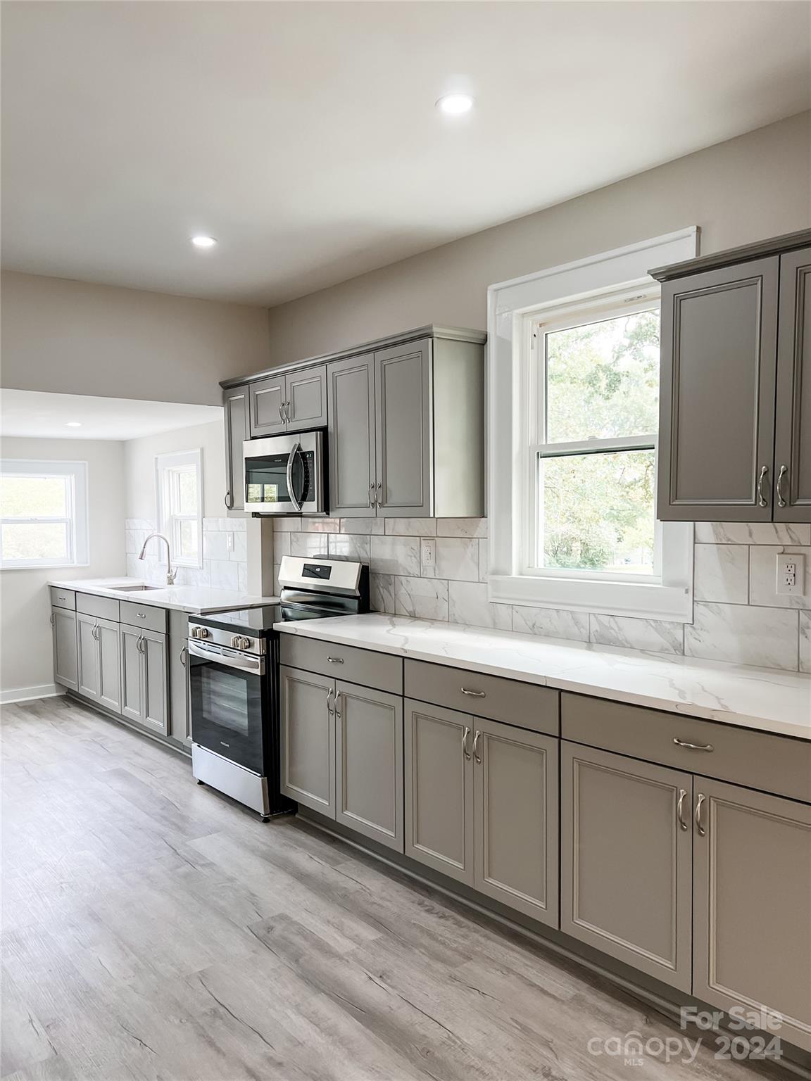 816 Laton Road Albemarle, NC 28001 - Photo 25 of 28 a kitchen with stainless steel appliances granite countertop white cabinets a sink a stove a window and wooden floors