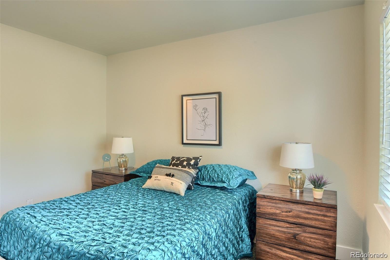 3075 South Grape Way Denver, CO 80222 - Photo 11 of 25 a bedroom with a bed and a lamp on table