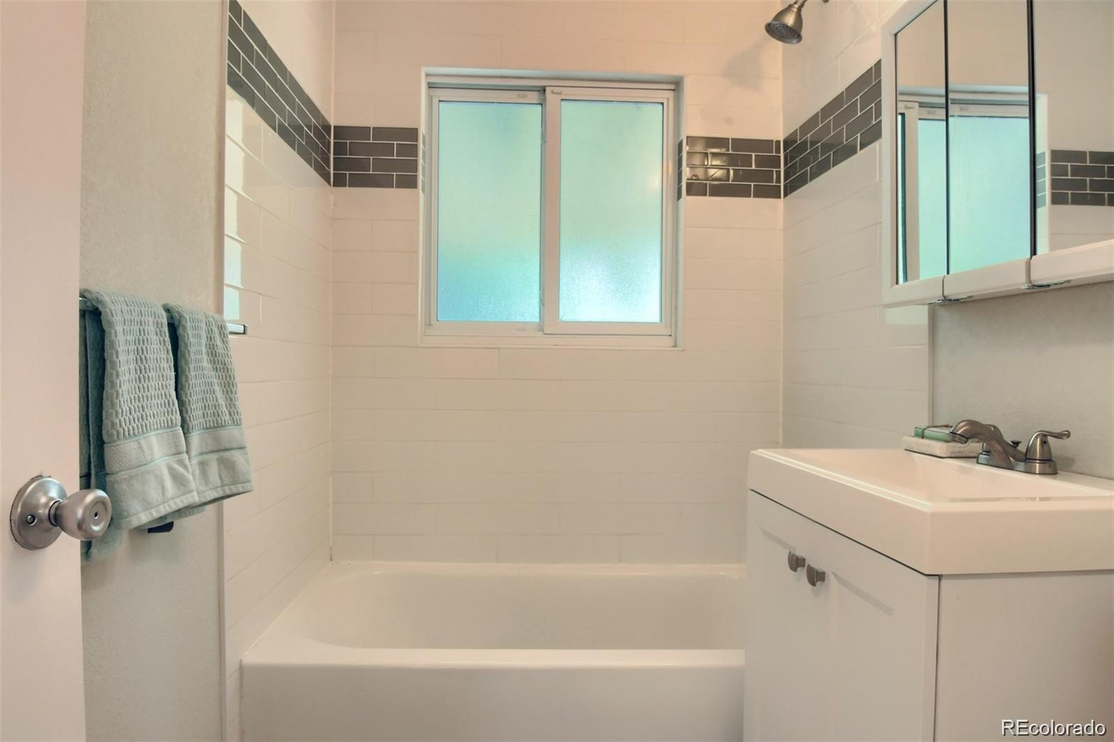 3075 South Grape Way Denver, CO 80222 - Photo 12 of 25 a bathroom with a sink a mirror and a bathtub