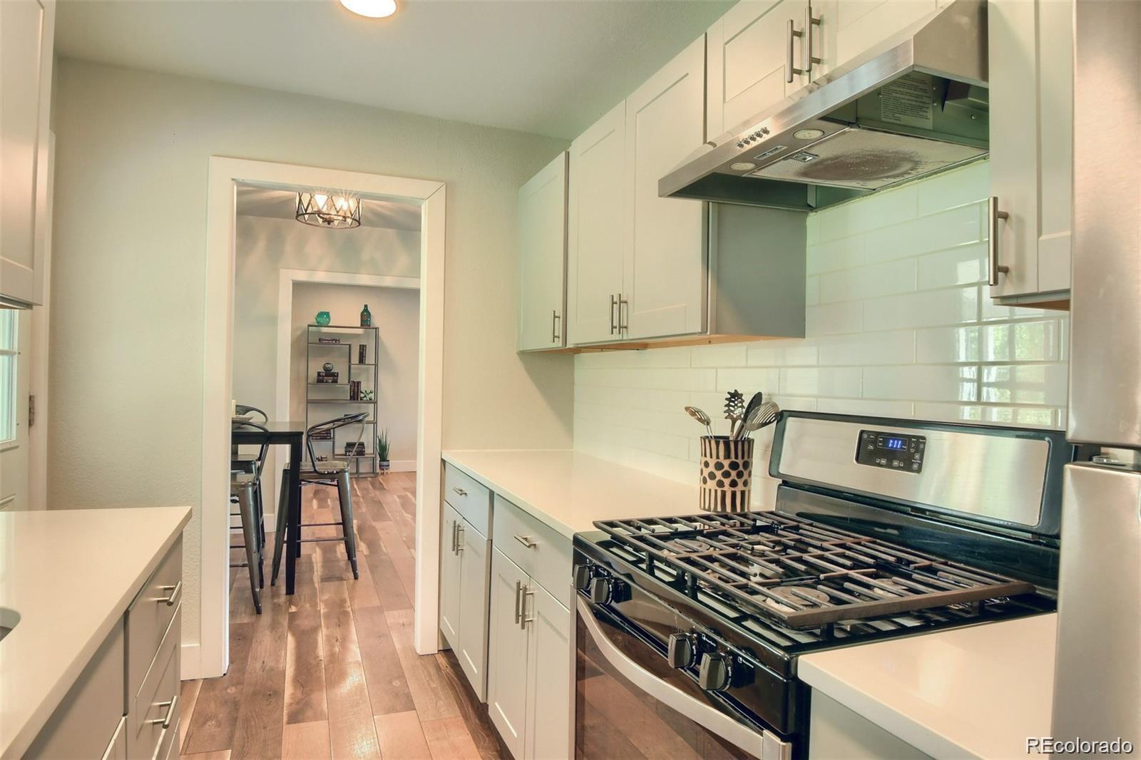 3075 South Grape Way Denver, CO 80222 - Photo 6 of 25 a kitchen with stainless steel appliances granite countertop a stove and a refrigerator