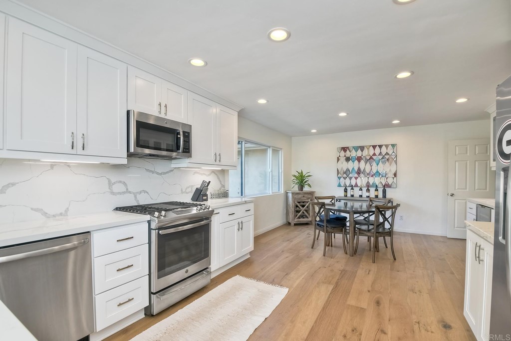 631 Dell Street Solana Beach, CA 92075 - Photo 21 of 36 a kitchen with white cabinets stainless steel appliances and dining table