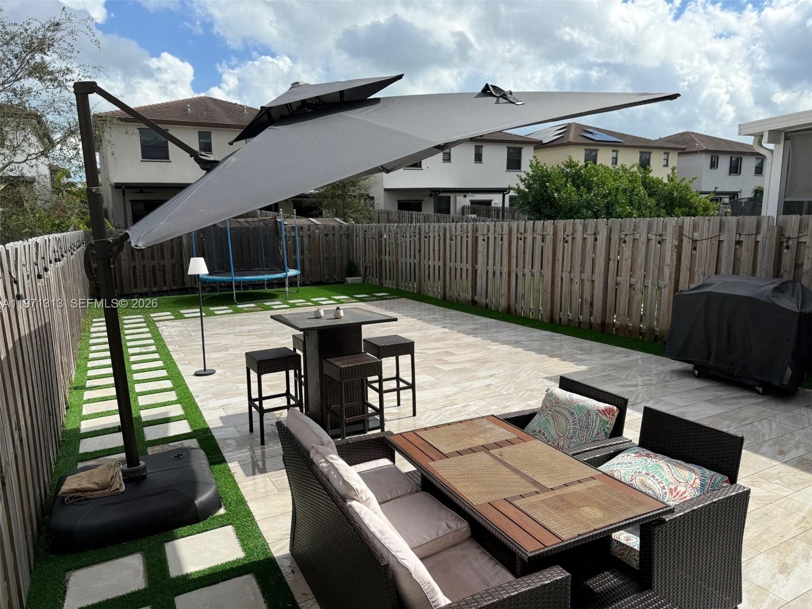 25265 Southwest 109th Avenue, Unit 25265 Homestead, FL 33032 - Photo 4 of 18 a view of a patio with table and chairs with wooden floor and fence