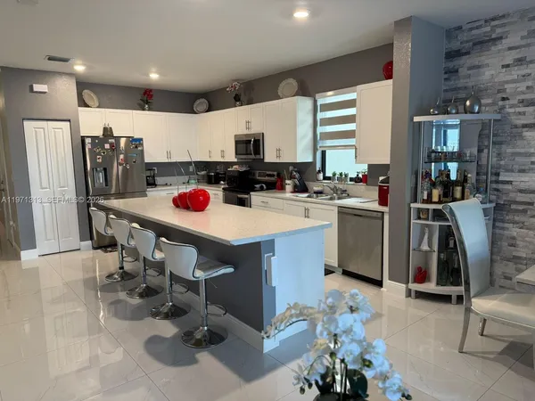 a kitchen with stainless steel appliances a sink a stove a refrigerator cabinets and dining table