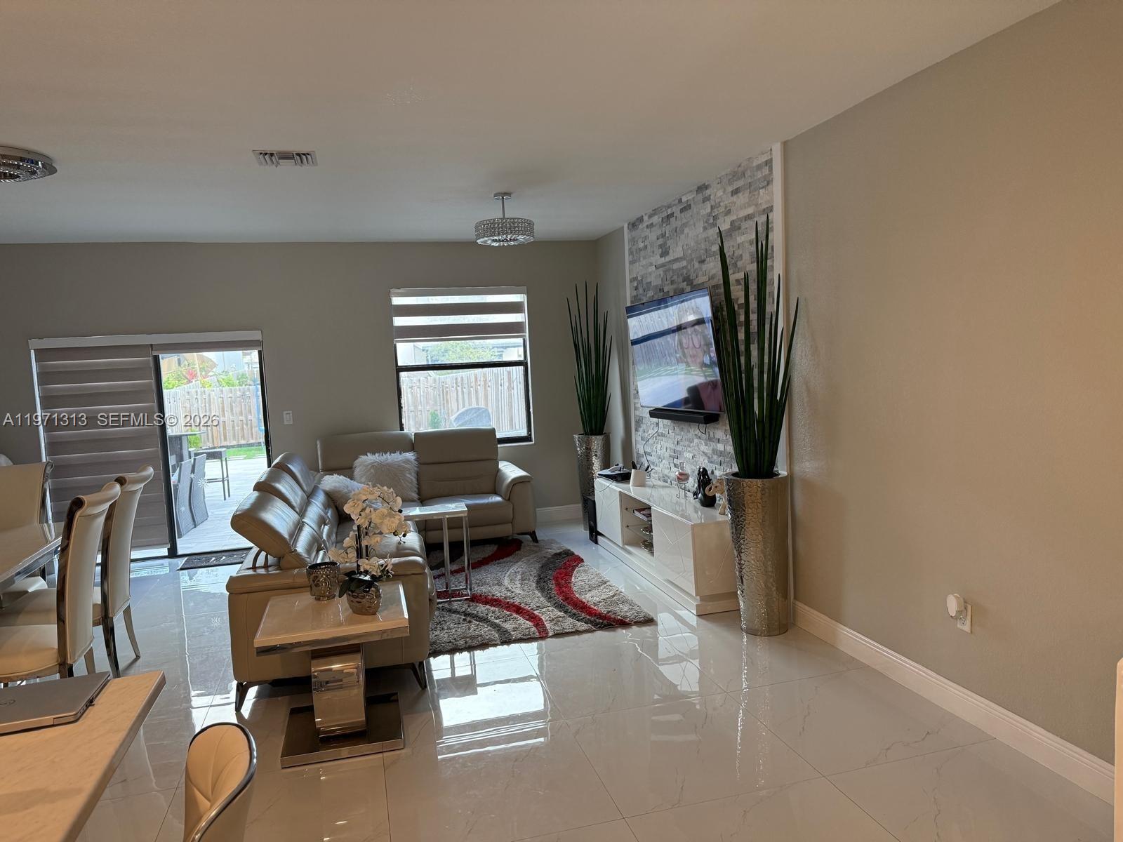25265 Southwest 109th Avenue, Unit 25265 Homestead, FL 33032 - Photo 7 of 18 a living room with furniture a window and a flat screen tv