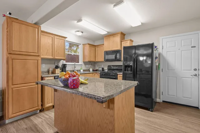 a kitchen with granite countertop stainless steel appliances a refrigerator a sink and cabinets