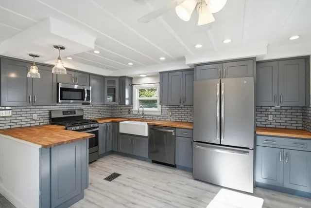 a kitchen with stainless steel appliances granite countertop a refrigerator a sink dishwasher a oven with white cabinets and wooden floor