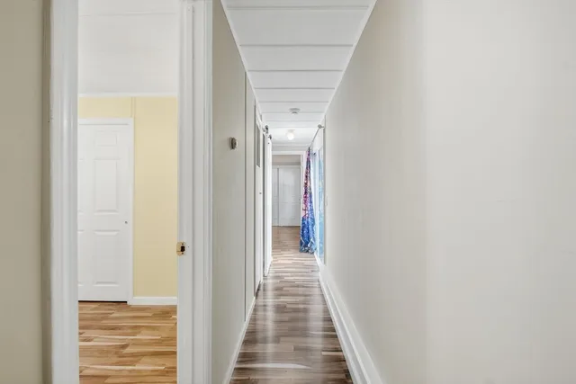 a view of a hallway with wooden floor and a bathroom