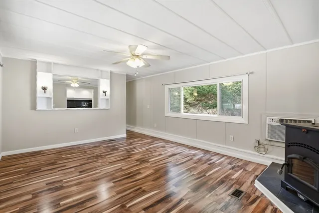 a view of an empty room with a window and wooden floor