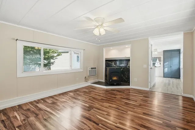 a view of a livingroom with wooden floor a ceiling fan and windows