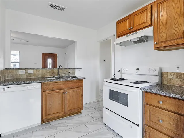 a kitchen with granite countertop stainless steel appliances white cabinets granite counter tops and a sink