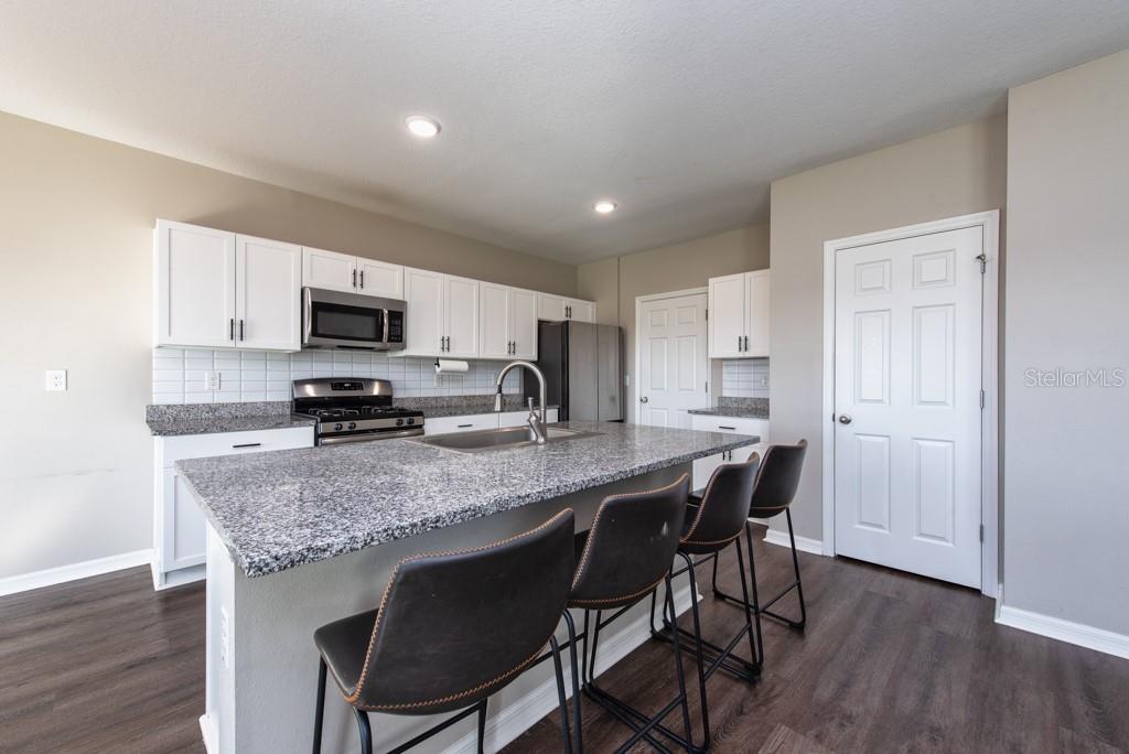 14617 Brumby Ridge Avenue Lithia, FL 33547 - Photo 11 of 46 a kitchen with stainless steel appliances granite countertop a table chairs sink refrigerator and microwave