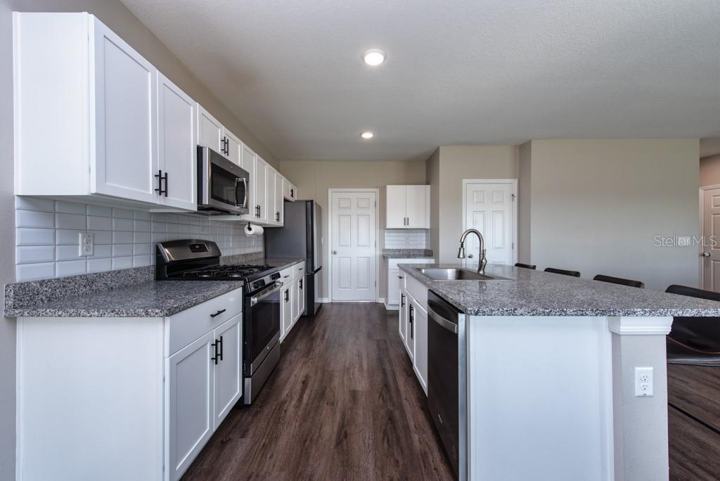 14617 Brumby Ridge Avenue Lithia, FL 33547 - Photo 12 of 46 a kitchen with stainless steel appliances granite countertop a sink stove microwave and cabinets