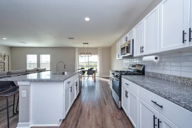 a kitchen with stainless steel appliances granite countertop lots of counter top space and wooden floor