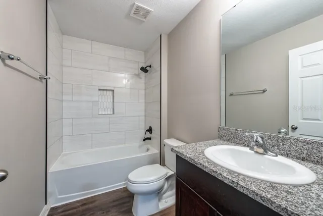 a bathroom with a granite countertop sink toilet and shower