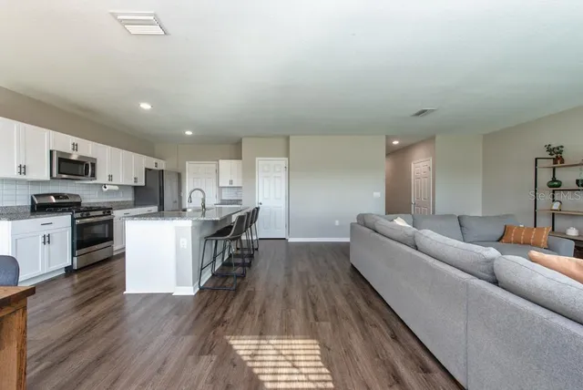 a living room with stainless steel appliances furniture and a kitchen view