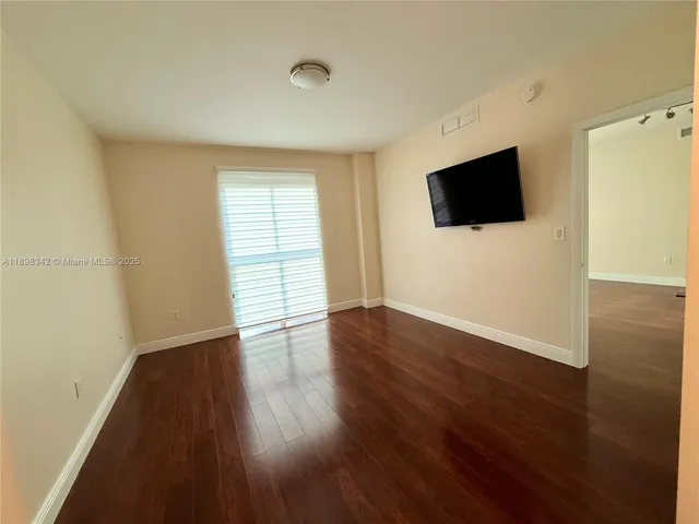 a view of a livingroom with wooden floor and a flat screen tv