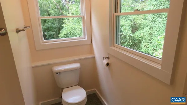 a white toilet sitting in a bathroom next to a window