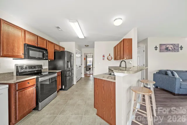 a kitchen with stainless steel appliances granite countertop a stove top oven a sink dishwasher a dining table and chairs with wooden floor