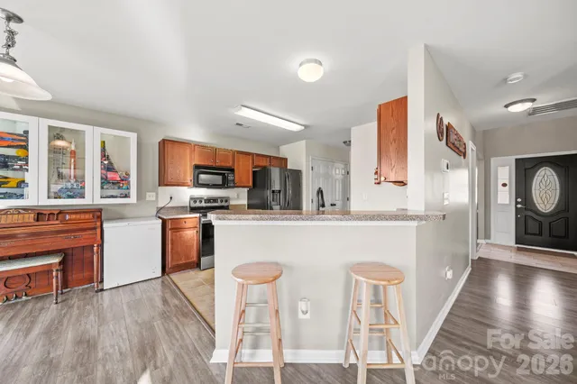 a kitchen with stainless steel appliances granite countertop a refrigerator a stove top oven a sink dishwasher and white cabinets with wooden floor
