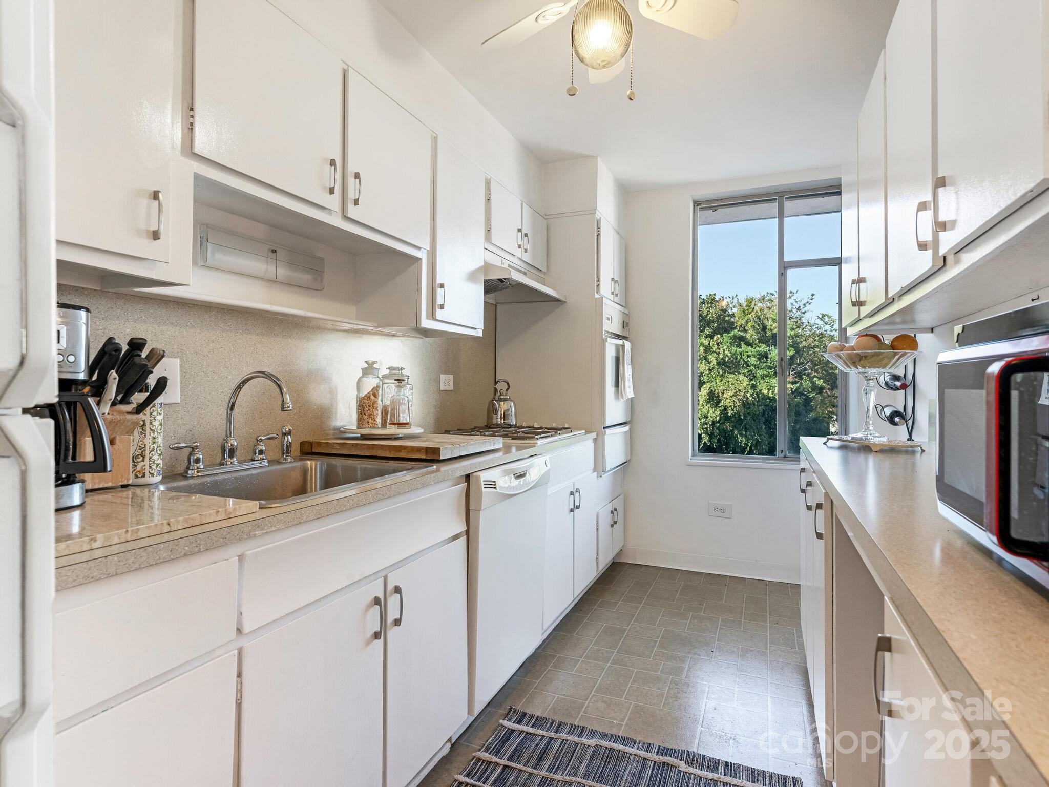1300 Queens Road, Unit 401 Charlotte, NC 28207 - Photo 14 of 21 a kitchen with white cabinets and appliances